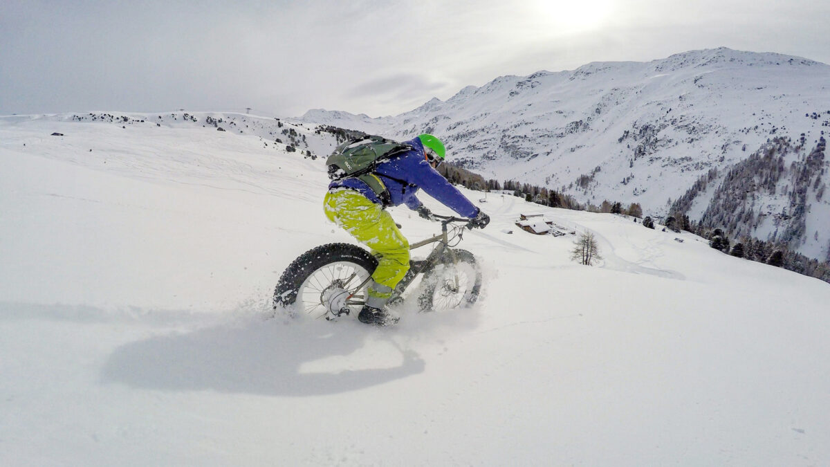 Radfahrer auf einem Fatbike unterwegs auf einem verschneiten Winterwanderweg in Davos